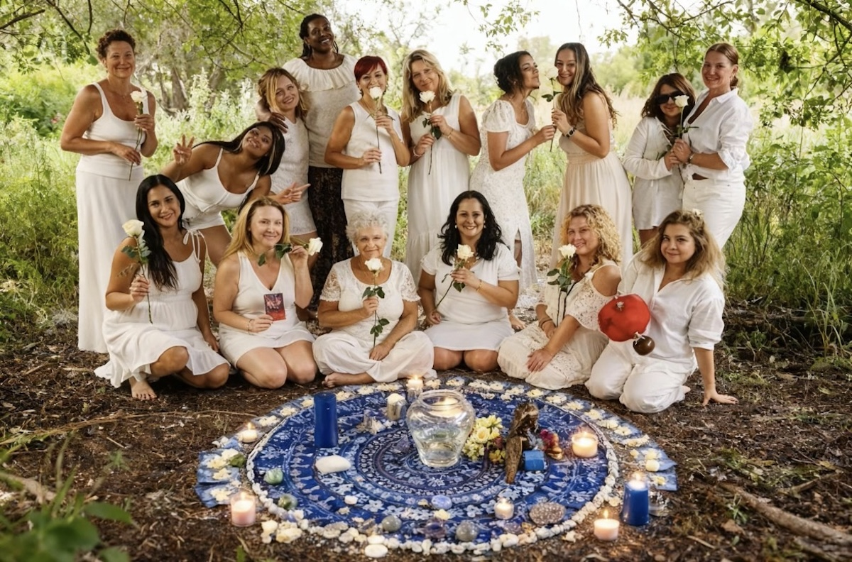 Women of La Femme Rose in white holding white roses around a ceremonial altar in a forest clearing