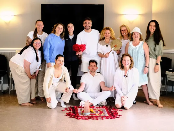 The circle group gathered in white around a rug of rose petals after ceremony