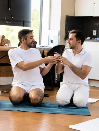 Two participants kneeling and passing a cup of cacao