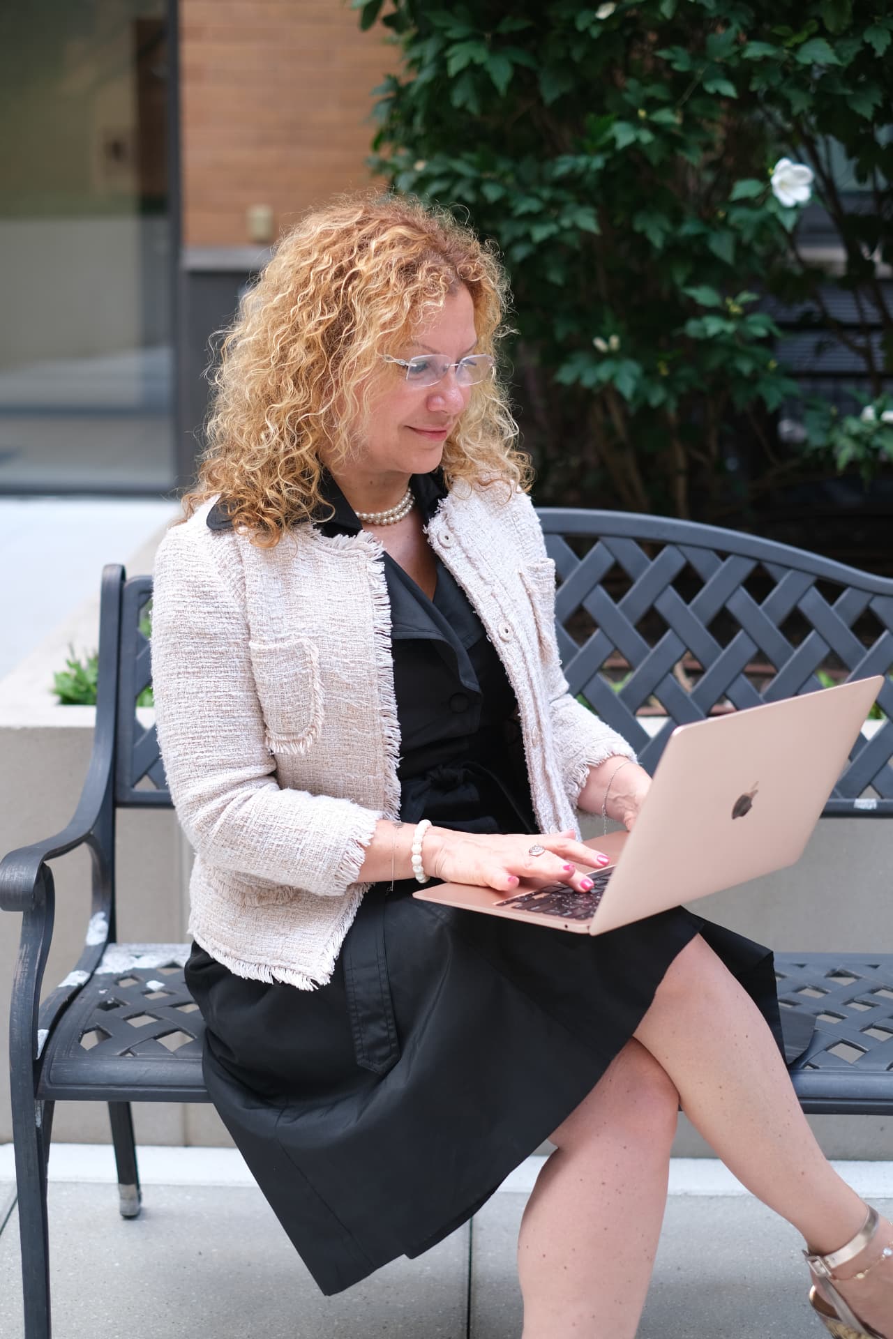 Irina Devi working on a laptop on a garden bench