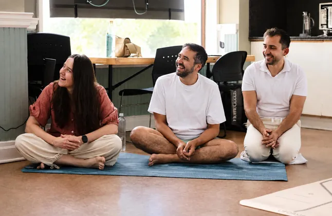 Participants sharing a laugh on the mat during a cacao ceremony